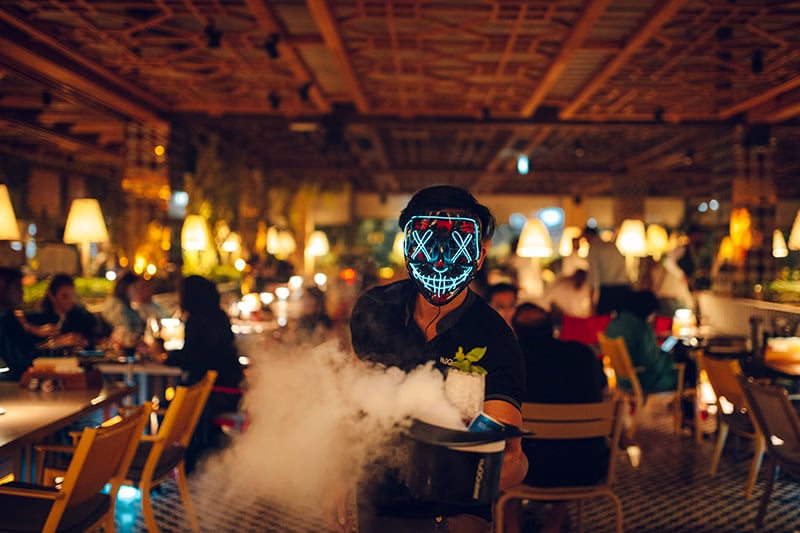 waitor with fun mask on holding food with smoke